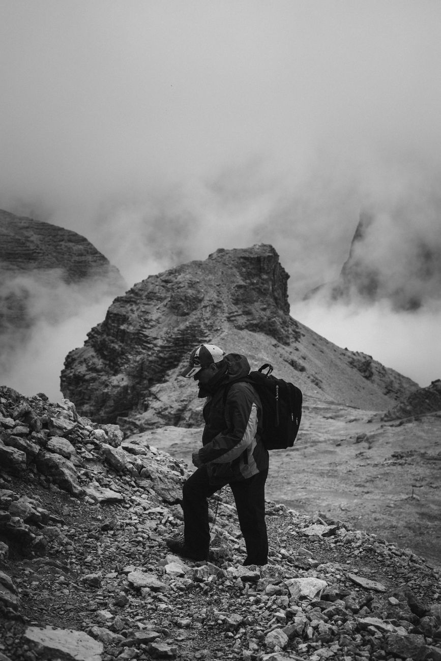 Hiker looking across dramatic misty alpine peaks